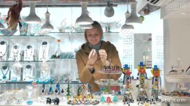 年轻微笑的女游客在威尼斯的<strong>玻璃器皿</strong>和口罩商店挑选纪念品